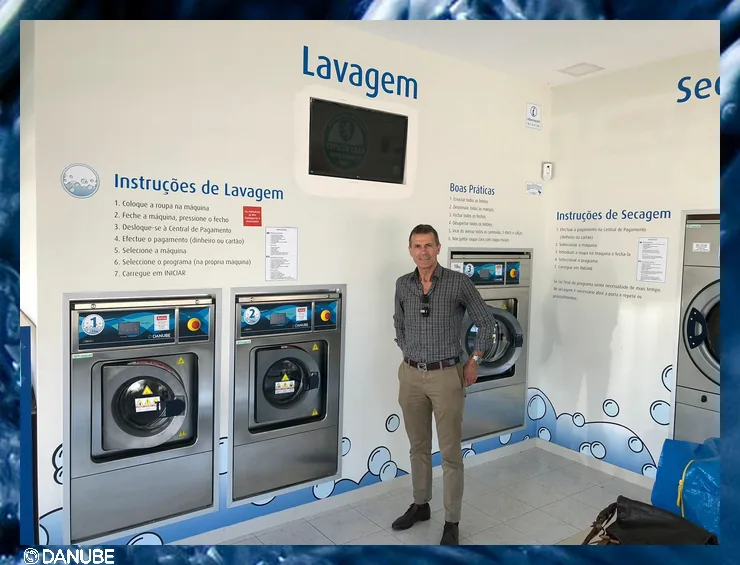 Interiorul unei spălătorii self-service: mașini de spălat Danube numerotate, montate în perete, cu instrucțiuni în portugheză