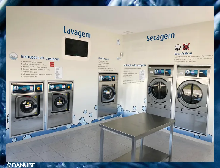 Spălătorie self-service: trei mașini de spălat și două uscătoare Danube numerotate, plus o masă din inox